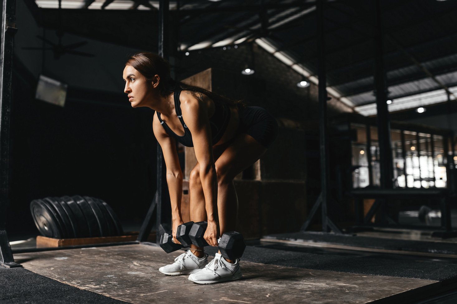 Woman Working Out with Dumbbells in the Dark Gym